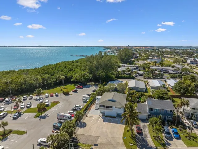 an aerial view of a city with lots of residential buildings ocean and mountain view in back