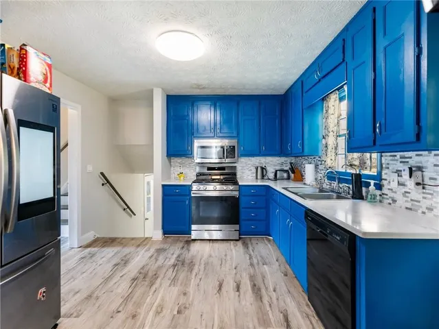 a kitchen with granite countertop wooden floors wooden cabinets and stainless steel appliances