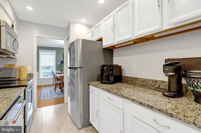 a kitchen with stainless steel appliances granite countertop a refrigerator a stove and a sink