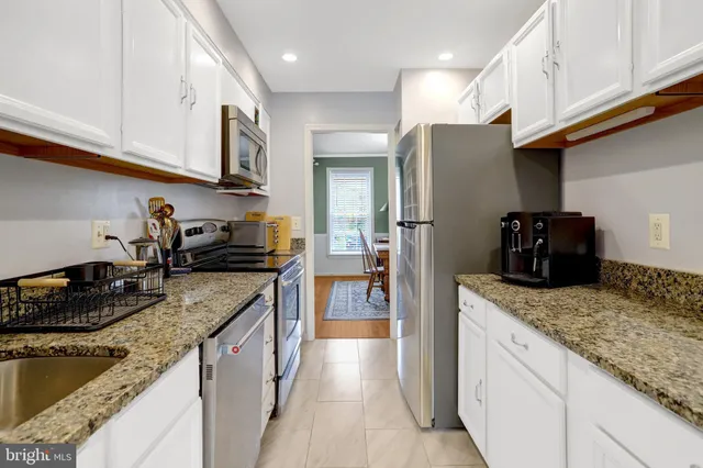 a kitchen with stainless steel appliances granite countertop a sink a stove and a refrigerator
