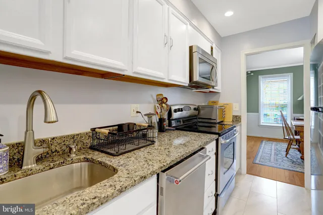 a kitchen with granite countertop a sink stainless steel appliances and cabinets