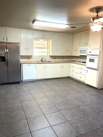 a large kitchen with white cabinets and white appliances