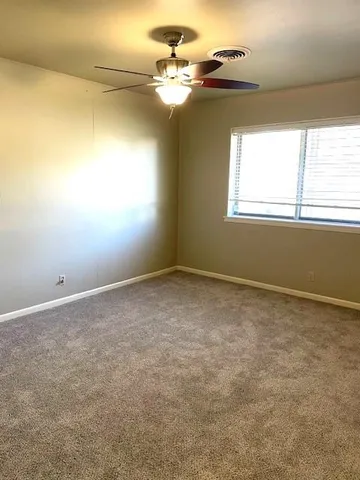 an empty room with windows and chandelier fan