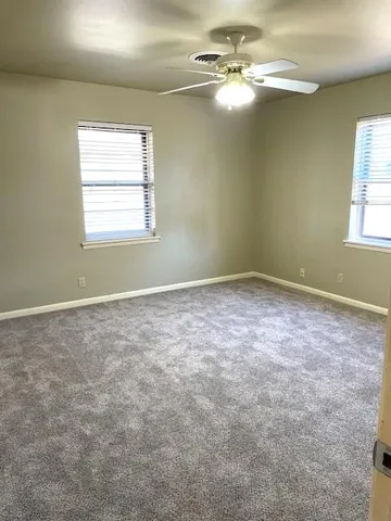 an empty room with windows and fan