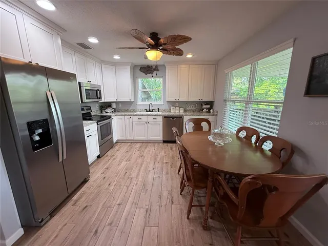 a kitchen with refrigerator a sink dishwasher a stove a refrigerator with a dining table and chairs with wooden floor