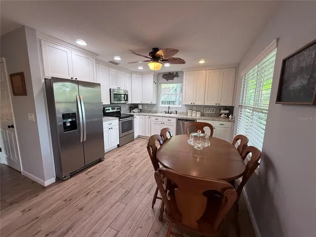 a kitchen with stainless steel appliances granite countertop a table chairs sink refrigerator and microwave