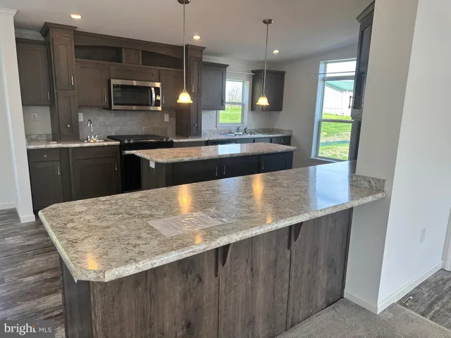 a large kitchen with kitchen island a counter space a sink a window and stainless steel appliances