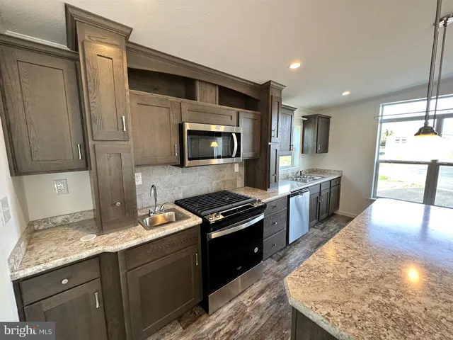 a kitchen with stainless steel appliances granite countertop a stove a sink and a microwave
