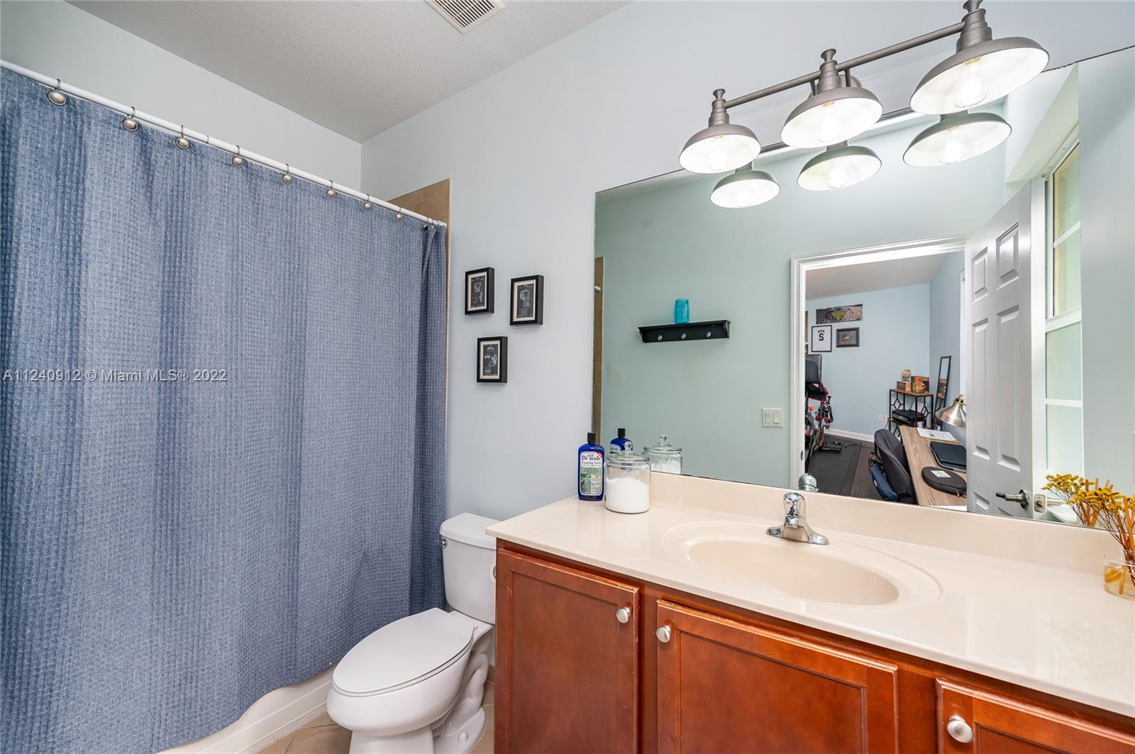 9031 Southwest 227th Street, Unit 9 Cutler Bay, FL 33190 - Photo 17 of 20 a bathroom with a sink a toilet mirror vanity and shower