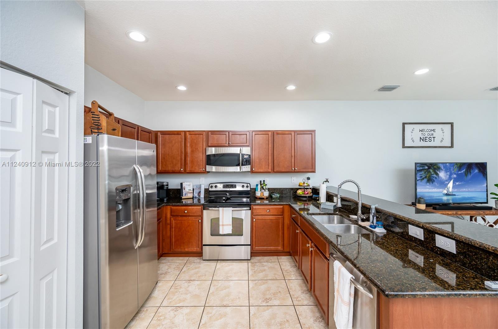 9031 Southwest 227th Street, Unit 9 Cutler Bay, FL 33190 - Photo 5 of 20 a large kitchen with stainless steel appliances granite countertop a stove top oven a sink dishwasher a refrigerator and a cabinets