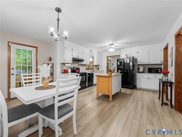 a kitchen with stainless steel appliances kitchen island granite countertop a refrigerator a stove top oven and a dining table with wooden floor