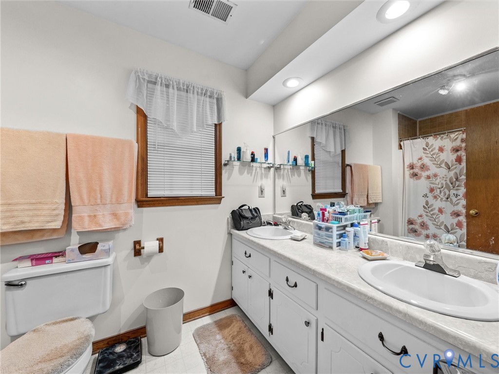 7706 Northern Dancer Court Midlothian, VA 23112 - Photo 19 of 40 a bathroom with a double vanity sink toilet mirror and window