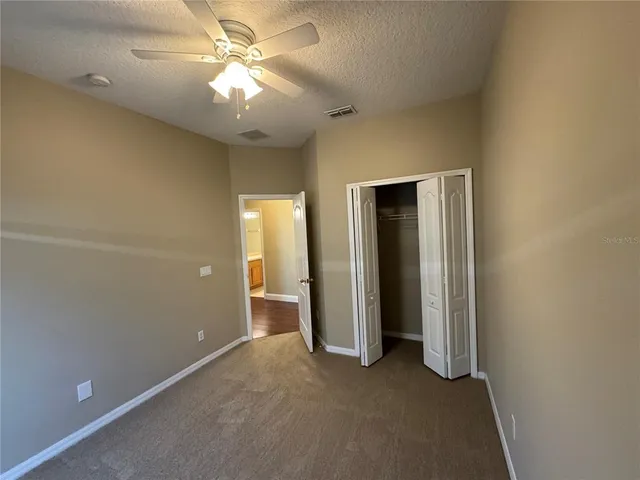 an empty room with closet and a ceiling fan