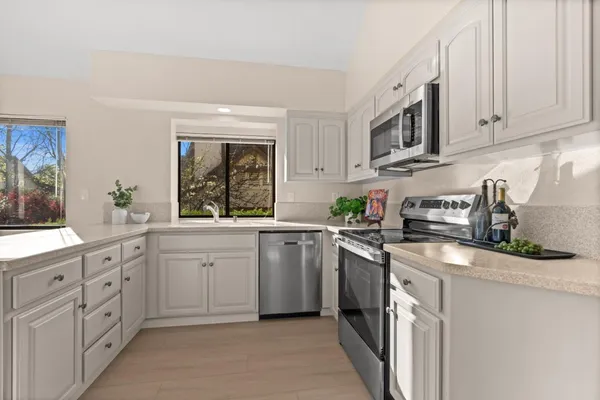 a kitchen with white cabinets sink and window