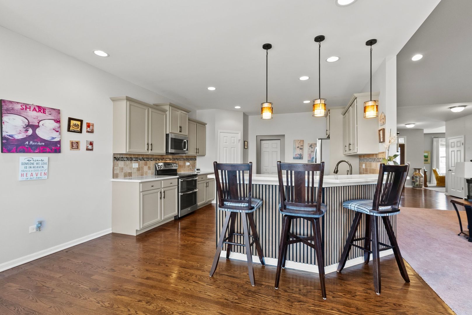 428 East Frontier Drive Minooka, IL 60447 - Photo 8 of 39 a kitchen with stainless steel appliances kitchen island granite countertop a table chairs and a wooden floor