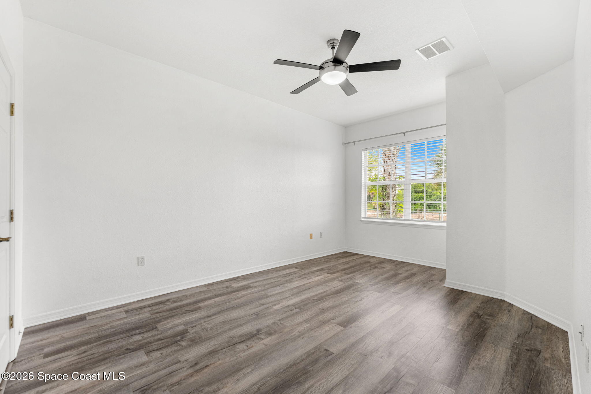 110 Turpial Way, Unit 106 Melbourne, FL 32901 - Photo 19 of 50 an empty room with wooden floor fan and windows