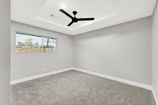 an empty room with windows and ceiling fan