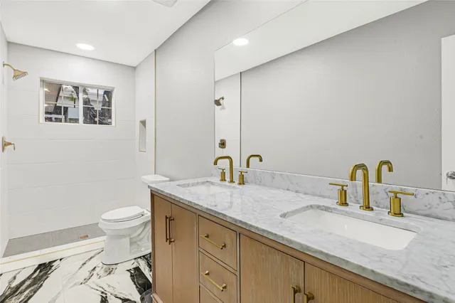 a bathroom with a granite countertop sink a toilet and a mirror