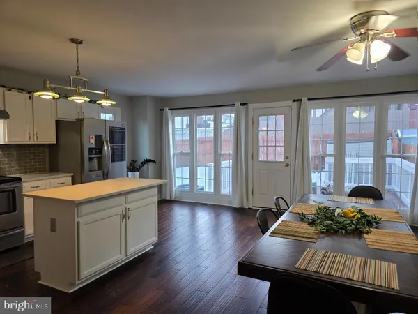 a kitchen with stainless steel appliances granite countertop a stove a sink dishwasher and a dining table with wooden floor