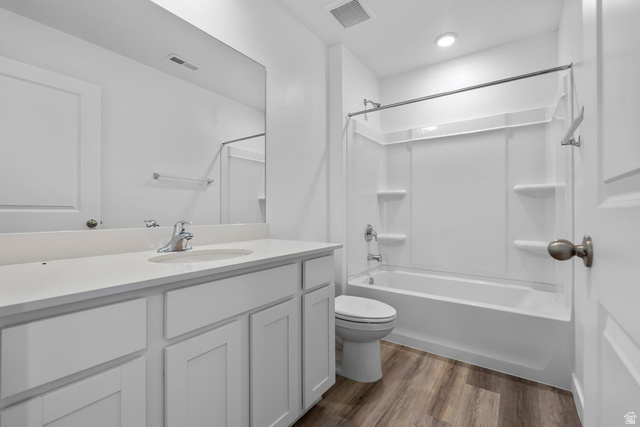 2133 Wolverine Way, Unit 2440 Washington, UT 84780 - Photo 12 of 39 Bathroom featuring a single vanity with a solid surface countertop, white cabinetry, a large wall-mounted mirror, a tub/shower combination, and wood-finish flooring