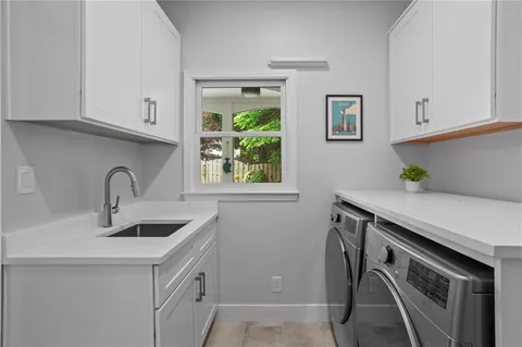 a kitchen with stainless steel appliances a sink a stove and white cabinets with wooden floor