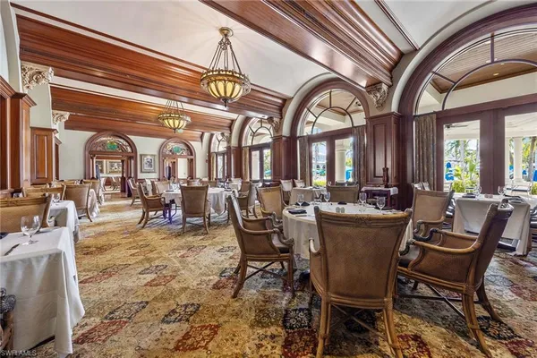 a view of a dining room and livingroom with furniture wooden floor a rug a painting and a chandelier