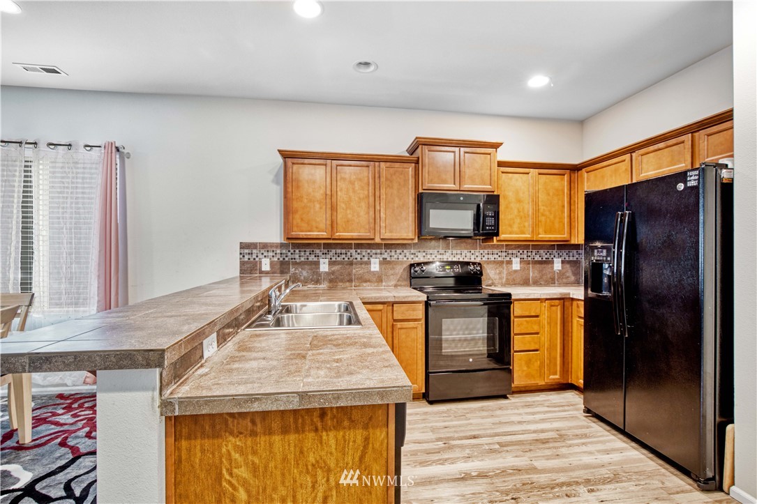 4866 East R Street Tacoma, WA 98404 - Photo 22 of 25 a kitchen with granite countertop stainless steel appliances and wooden cabinets