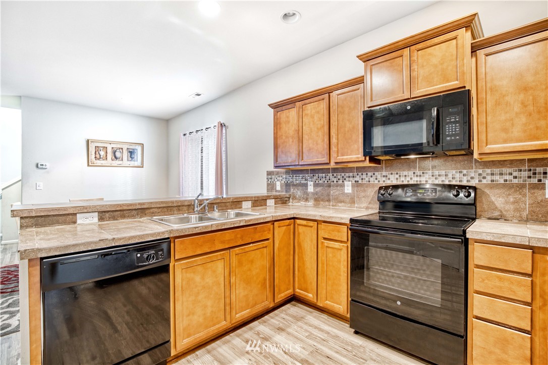 4866 East R Street Tacoma, WA 98404 - Photo 23 of 25 a kitchen with stainless steel appliances granite countertop a stove sink and microwave
