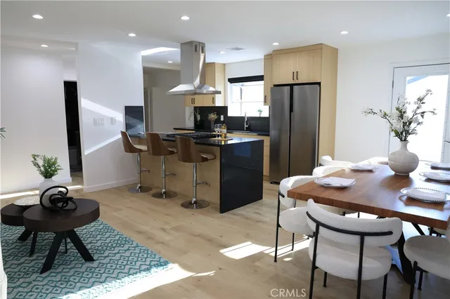 a kitchen with stainless steel appliances kitchen island granite countertop a dining table chairs and a refrigerator