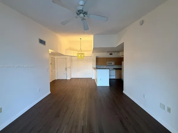 an empty room with wooden floor and a ceiling fan