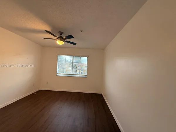 an empty room with wooden floor fan and windows