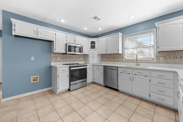 a kitchen with white cabinets stainless steel appliances and a window