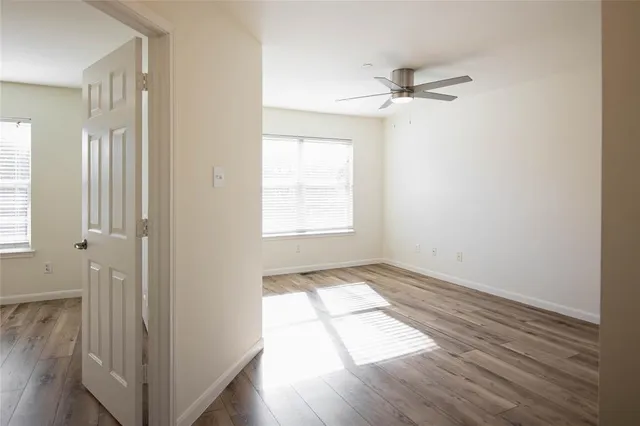 a view of empty room with wooden floor and fan