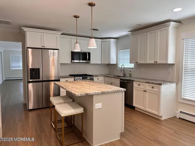 a kitchen with a refrigerator a microwave a sink and wooden floor