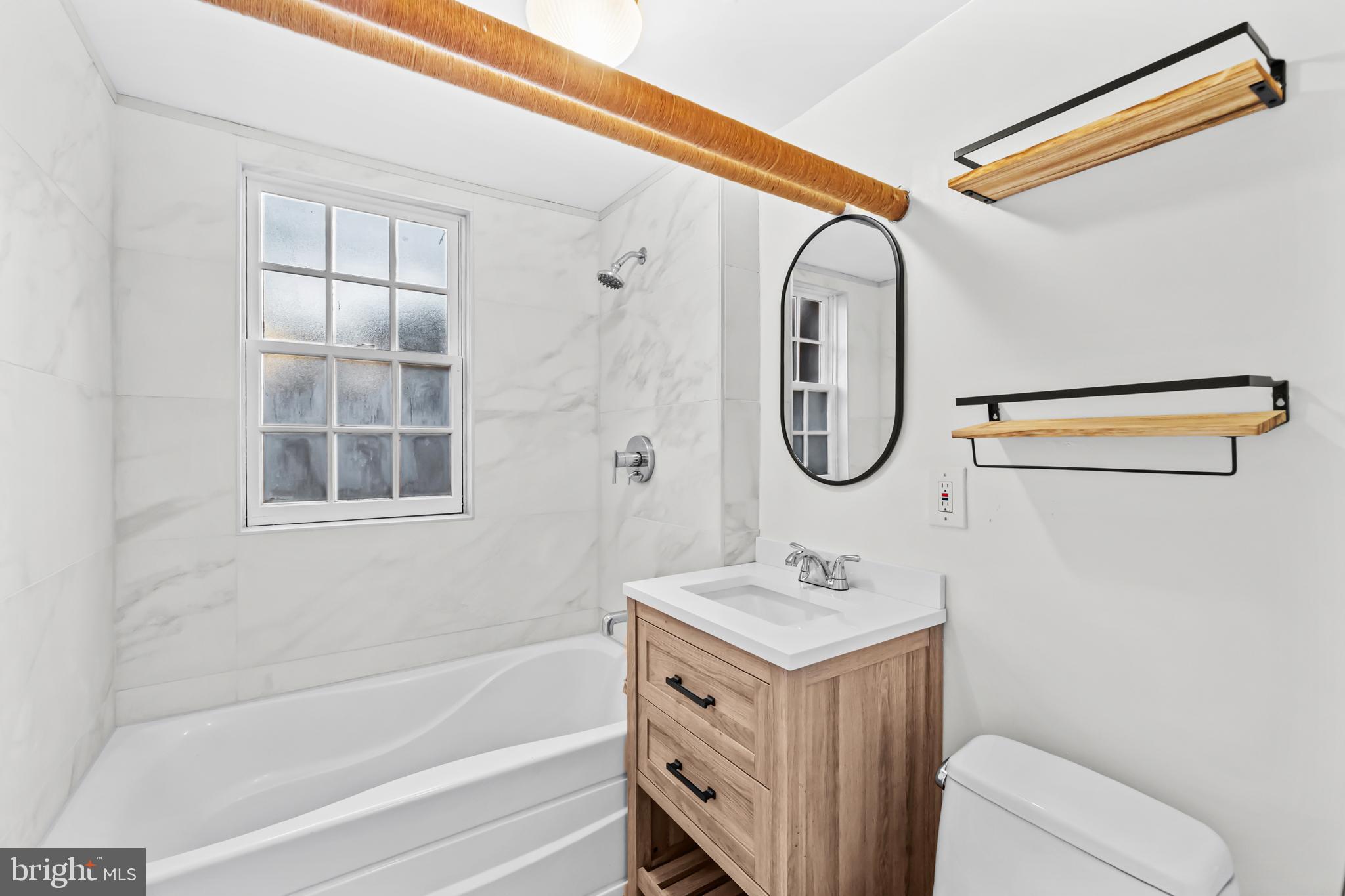 3001 Porter Street Northwest, Unit 100 Washington, DC 20008 - Photo 15 of 22 a bathroom with a granite countertop tub sink and mirror