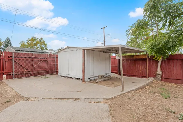 a backyard of a house with a barn plants and large tree