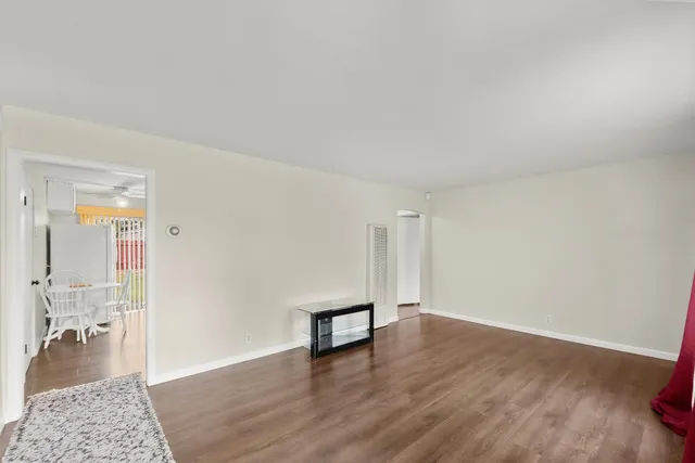 a view of an empty room and wooden floor and a bathroom