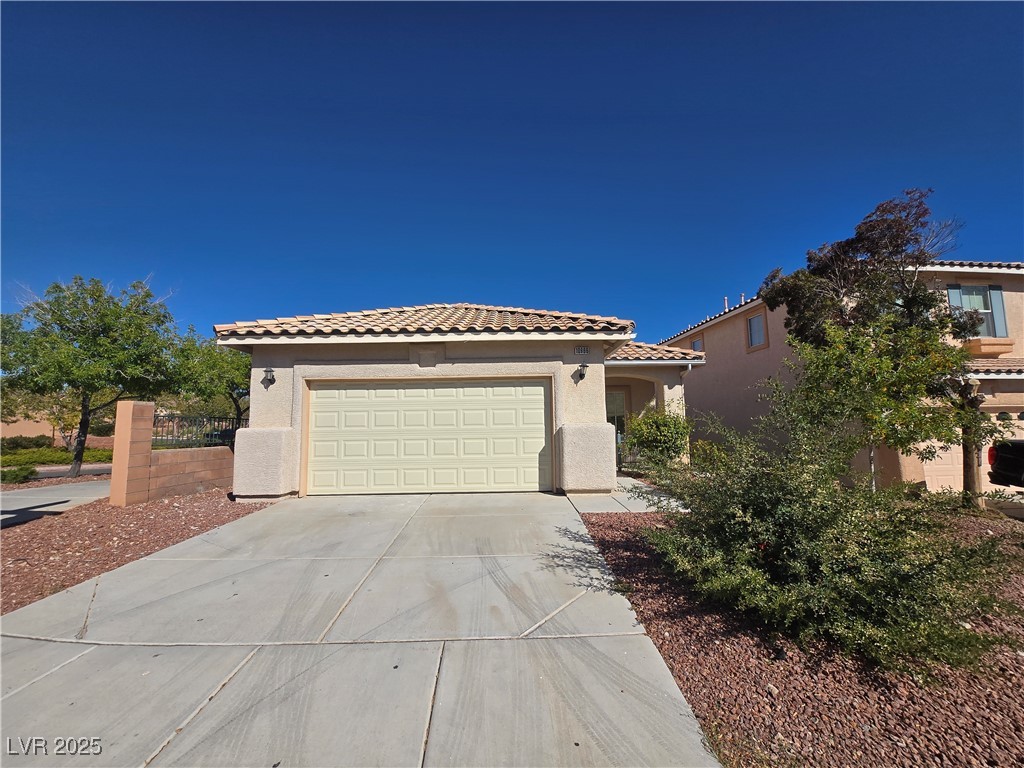 10966 Sutter Hills Avenue Las Vegas, NV 89144 - Photo 2 of 18 Mediterranean / spanish-style home featuring stucco siding, a tile roof, driveway, and a garage