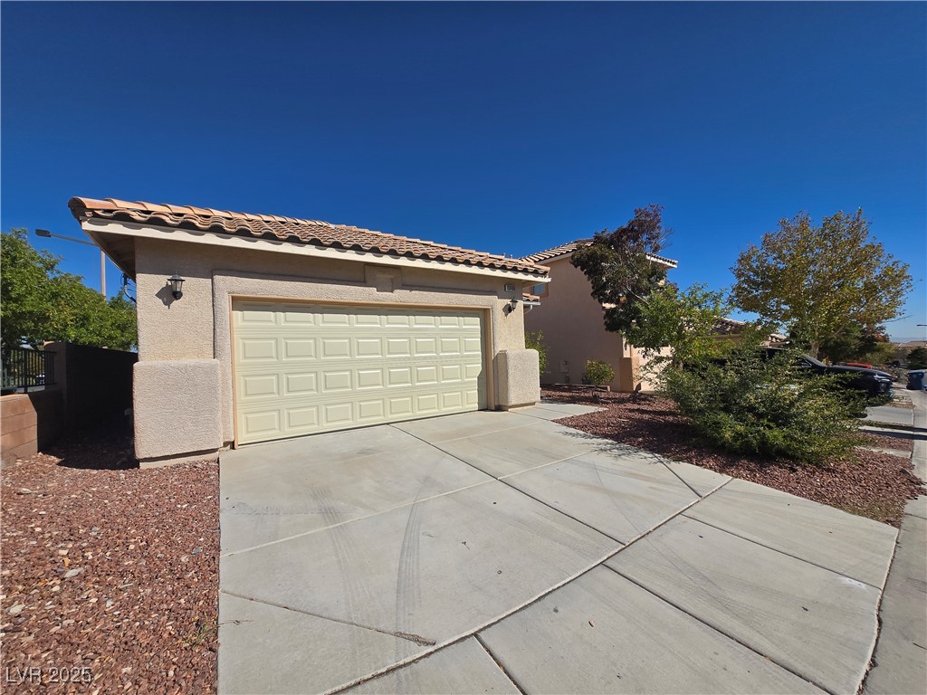 10966 Sutter Hills Avenue Las Vegas, NV 89144 - Photo 3 of 18 View of front of property with stucco siding, a tiled roof, driveway, and an attached garage