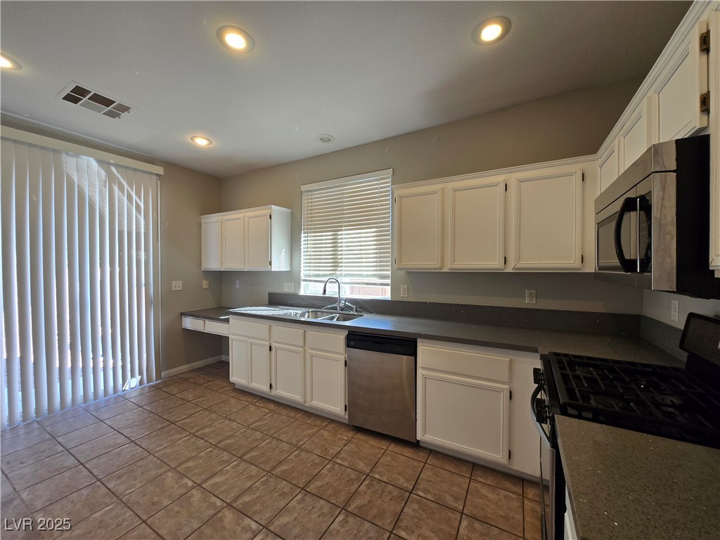 10966 Sutter Hills Avenue Las Vegas, NV 89144 - Photo 6 of 18 Kitchen featuring stainless steel appliances, white cabinets, dark tile patterned flooring, and recessed lighting