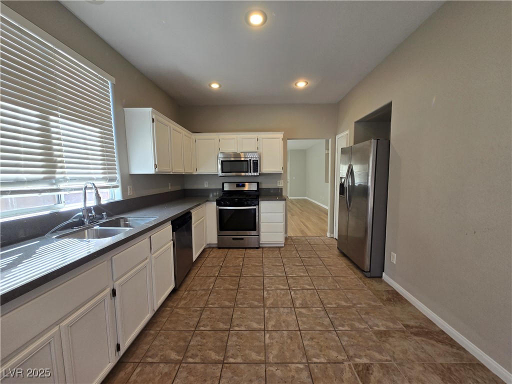 10966 Sutter Hills Avenue Las Vegas, NV 89144 - Photo 9 of 18 Kitchen featuring white cabinets, stainless steel appliances, dark countertops, recessed lighting, and dark tile patterned floors