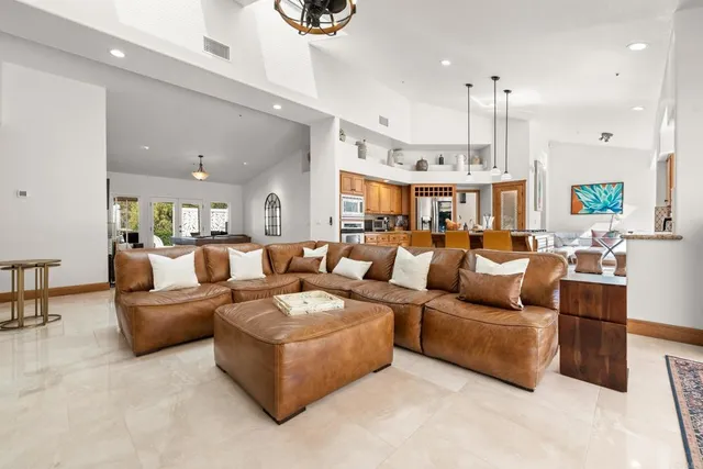 a living room with furniture kitchen view and a chandelier