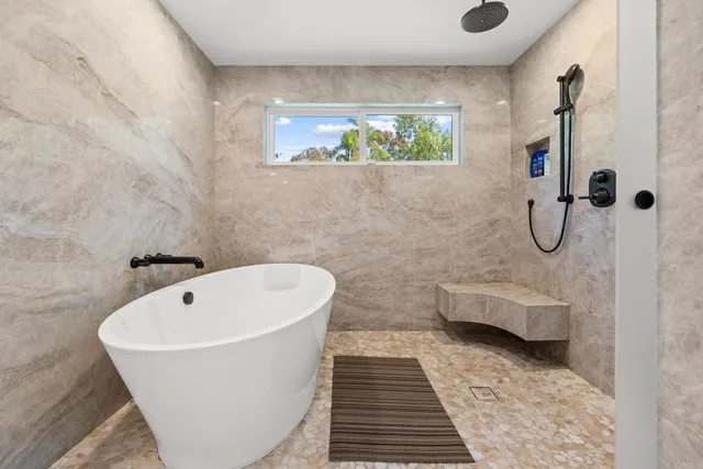 a bathroom with a white bath tub a window and a rug