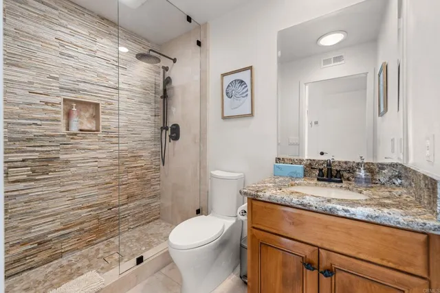 a bathroom with a granite countertop toilet sink and mirror