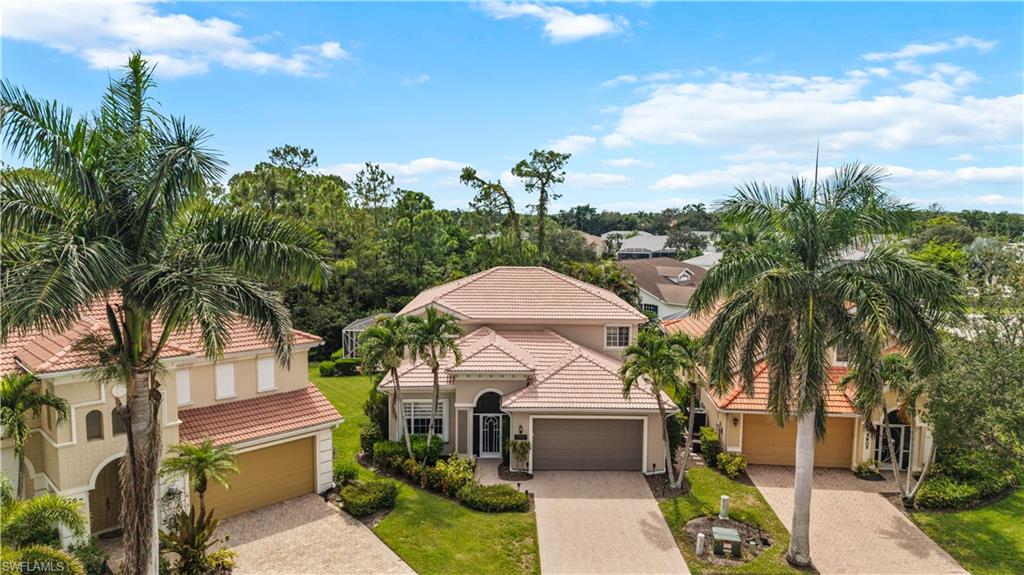 5801 Lago Villaggio Way Naples, FL 34104 - Photo 19 of 23 View of front of property featuring decorative driveway, a garage, a tile roof, and stucco siding
