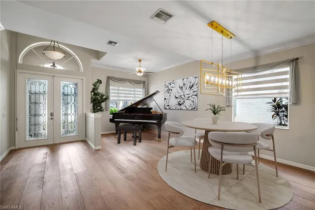 a dining room with wooden floor a chandelier a wooden table and chairs
