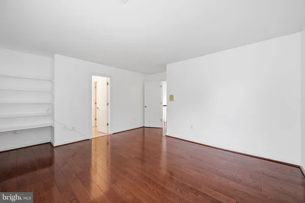 a view of an empty room with wooden floor and closet
