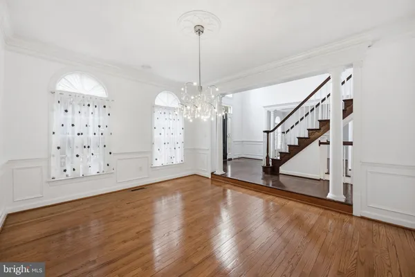 a view of an empty room with wooden floor and stairs