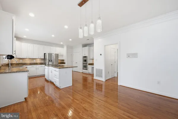 a large white kitchen with lots of counter space wooden floor and appliances