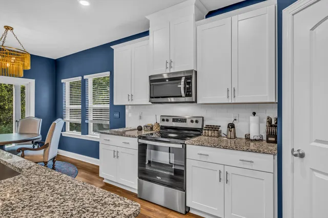 a kitchen with stainless steel appliances granite countertop a stove a sink and a microwave